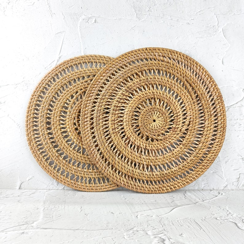 Two natural round spiral rattan placemats stacked together
